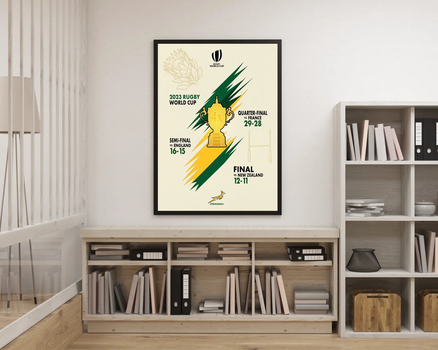 Framed poster of a rugby world cup event on a wall above a bookshelf.