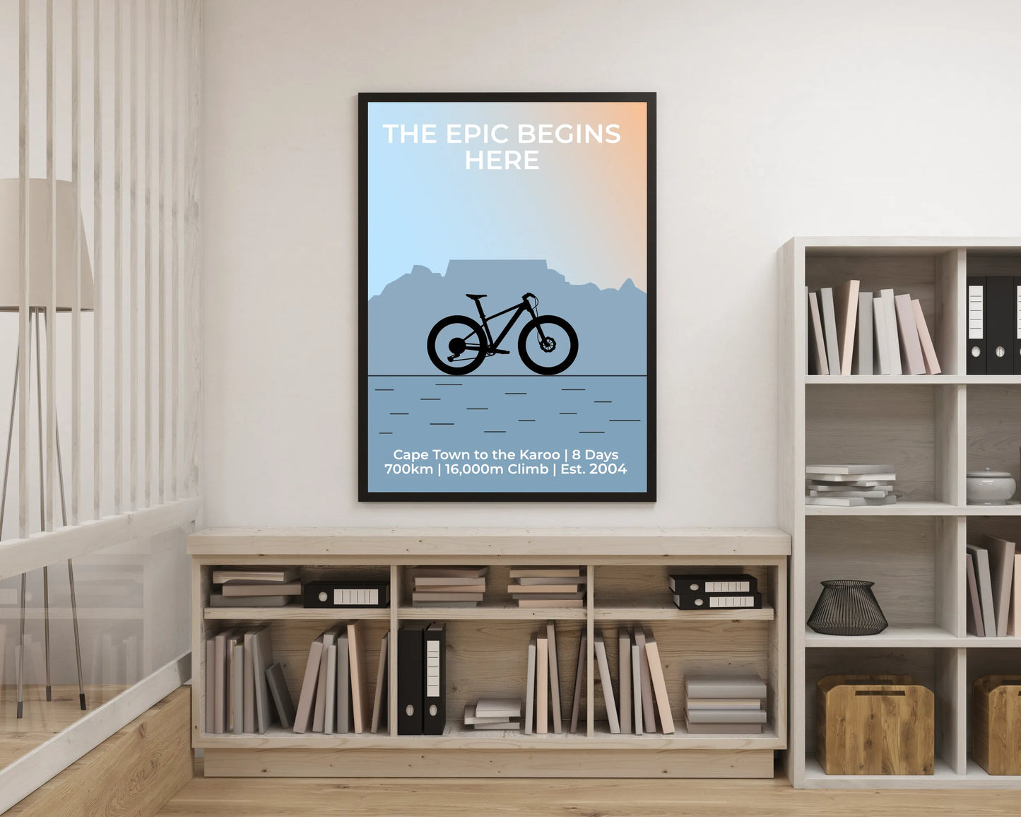 Framed poster with a bicycle design and text on a wall above a bookshelf.