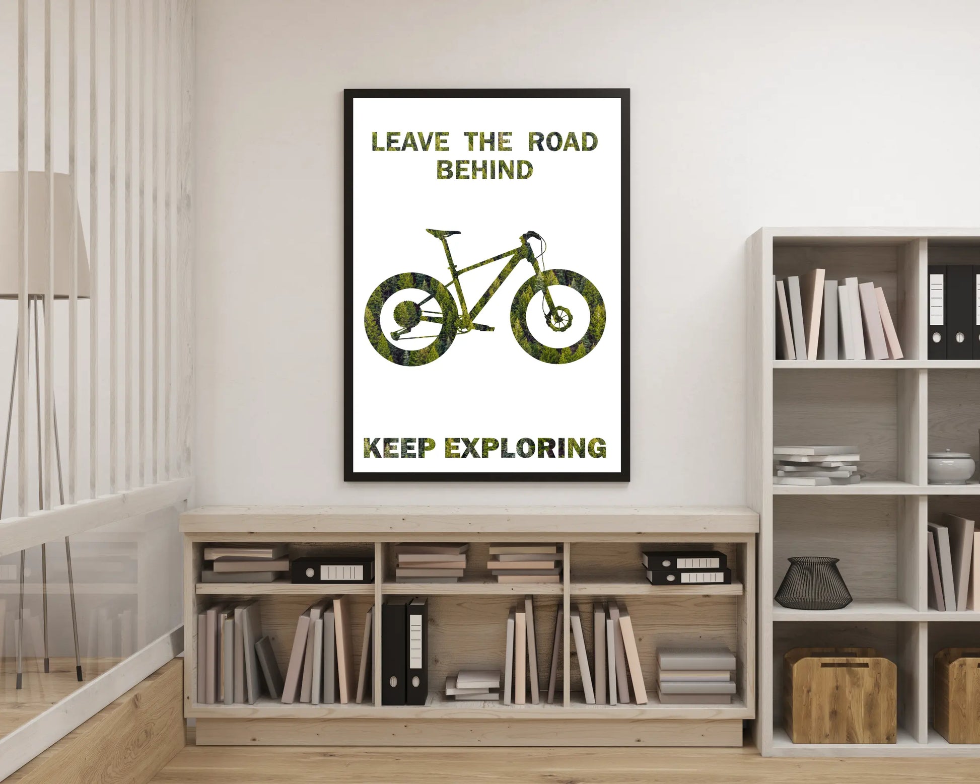 Poster with bicycle design and text 'Leave the road behind, keep exploring' on a wall in a room with bookshelves.